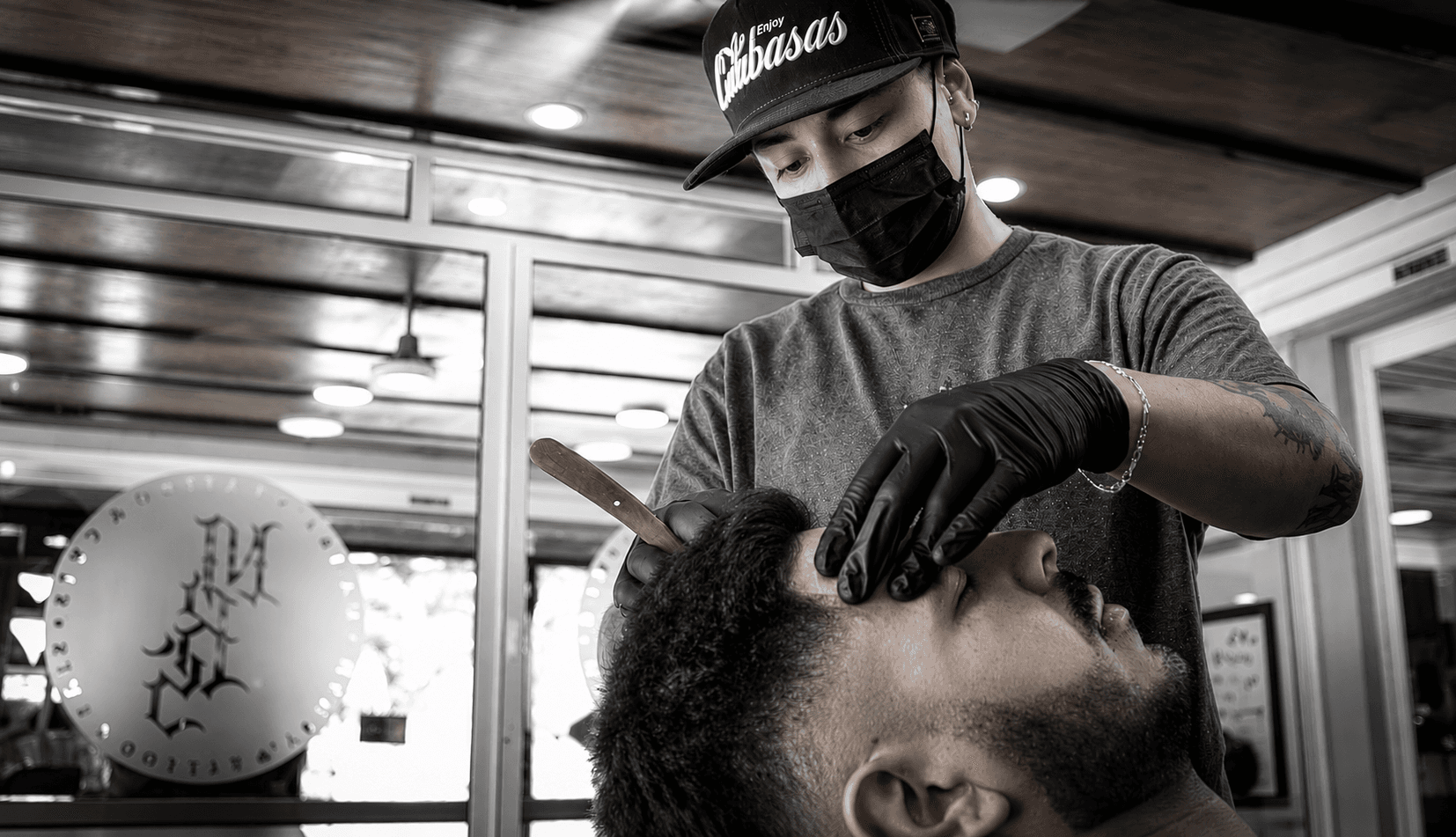 Barbero de Mambas realizando servicio con navaja en barbería