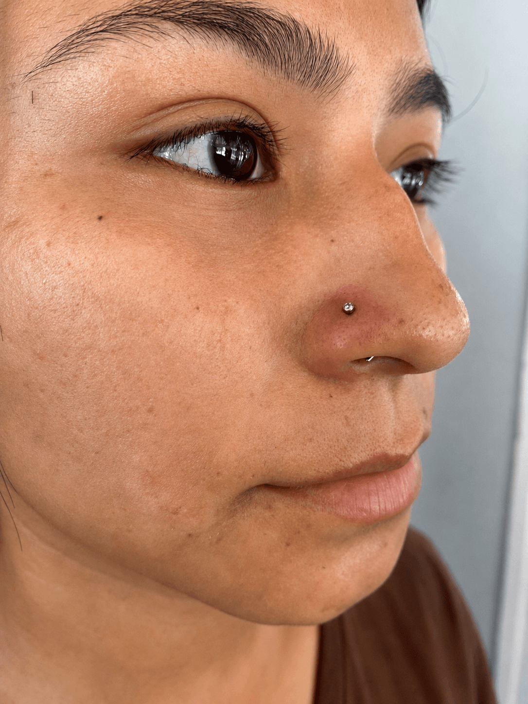 Piercing nostril con joyería discreta realizado por Mambas