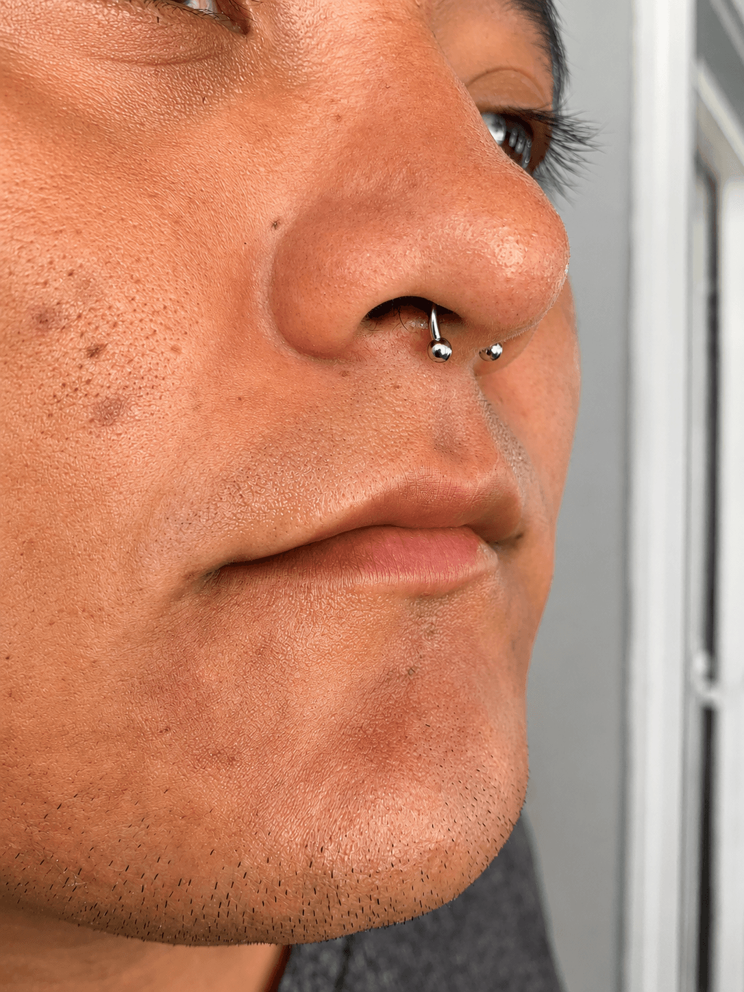 Piercing septum con joyería plateada realizado por Mambas